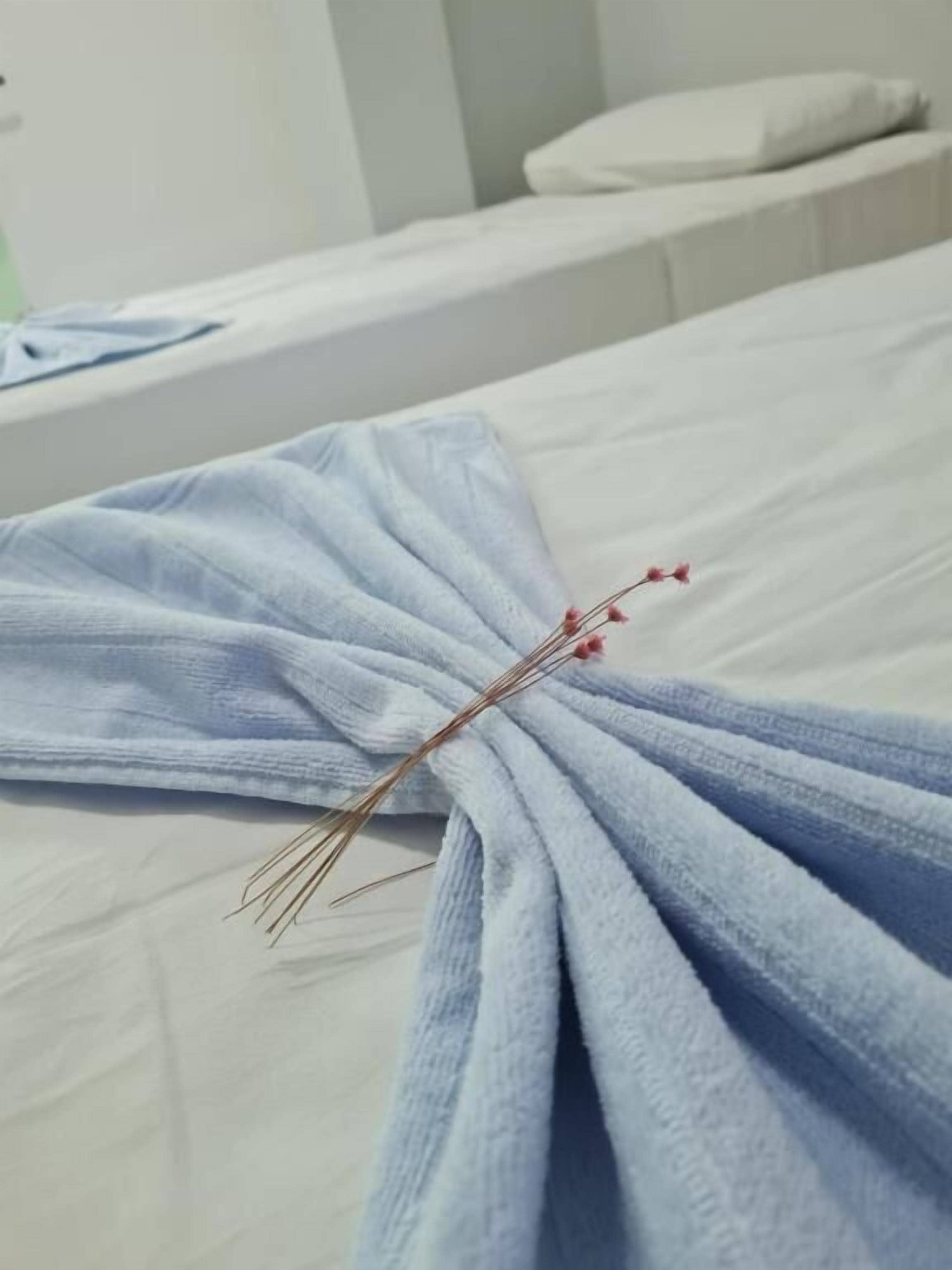 A neatly folded towel with a decorative twig on a bed.