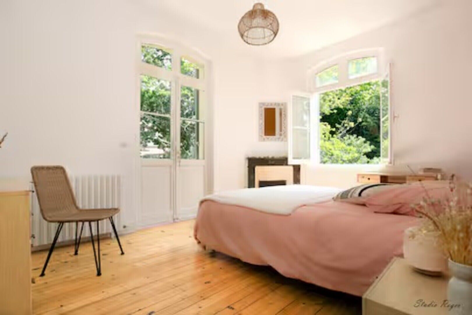 Une chambre à coucher comprenant un lit, une chaise, une commode et une fenêtre donnant sur un paysage verdoyant.