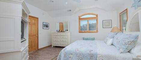 A bedroom with a bed, dresser, vanity, and a ceiling fan.