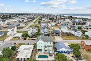 Un barrio residencial con casas, piscina y vista al océano.