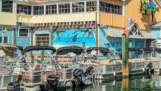 Un port de plaisance avec des bateaux amarrés, un bâtiment sur lequel on peut lire l’inscription « The Margaritaville », et un grand hôtel en arrière-plan.