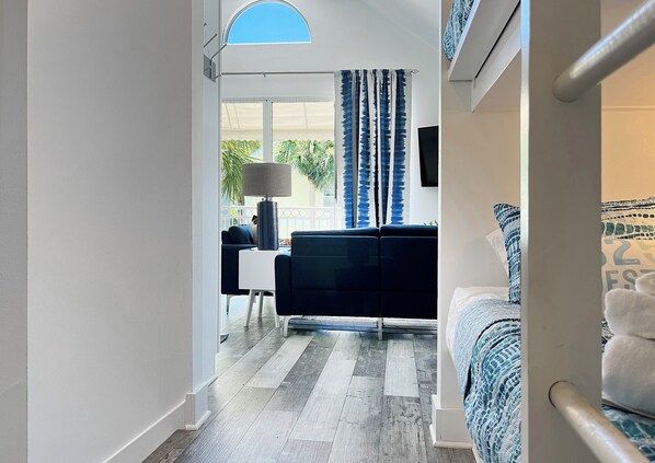 A modern hotel room with a balcony, a sofa, a desk, and a bed.