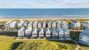 Un hotel frente a la playa con edificios de varios pisos, una playa arenosa y el océano al fondo.