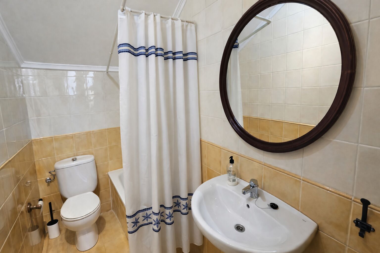 Un baño con inodoro, lavamanos y cortina de ducha.