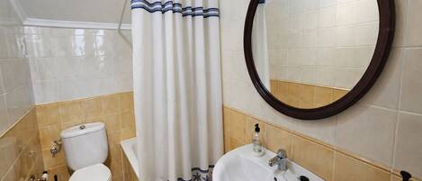 Un baño con inodoro, lavamanos y cortina de ducha.