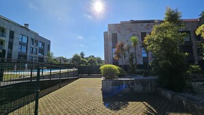 A courtyard with a swimming pool, a fenced area, and a building with stone facade and windows.