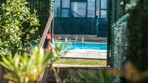 A swimming pool with a view of a building with large windows and a green fence.
