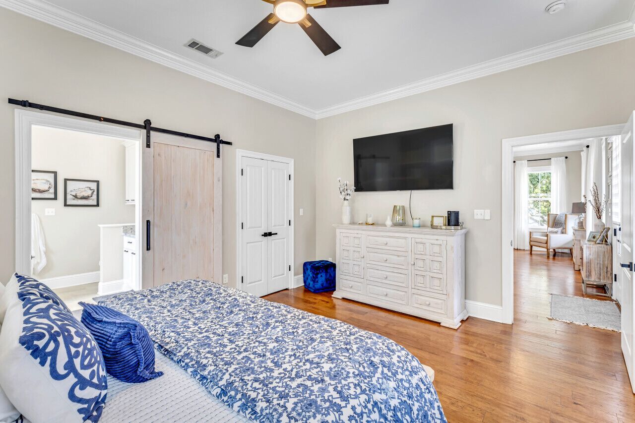 A bedroom with a bed, a dresser, a TV, and a sliding door.