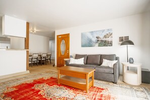 A living room with a sofa, coffee table, and a red patterned rug.