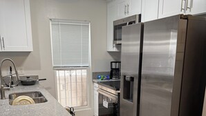 A modern kitchen with white cabinets, stainless steel appliances, and a granite countertop. - Stunning Oceanfront Venice Beach 2BR/2BA with Beach Views + Free Parking (Los Angeles)