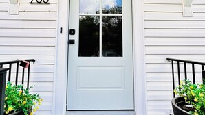 A white door with a number "708" above it, a welcome mat at the entrance, and two potted plants on either side. - Charming 2-bedroom house in Ardmore with AC, WiFi. Enjoy your stay (Ardmore)