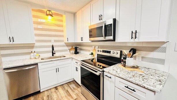 A modern kitchen with white cabinets, stainless steel appliances, and a herringbone-patterned backsplash. - Charming 2-bedroom house in Ardmore with AC, WiFi. Enjoy your stay (Ardmore)