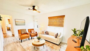 A living room with a wooden floor, a white sofa, two leather armchairs, a coffee table, and a ceiling fan. - Charming 2-bedroom house in Ardmore with AC, WiFi. Enjoy your stay (Ardmore)