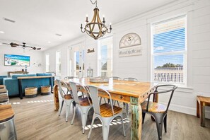 A spacious dining area with a wooden table and chairs, a chandelier, and large windows with blinds. - ☀️Private Pool~Sleeps 16~Front & Back Porch~Walk 2 Beach~Pet Friendly~Sealah🏖️ (Destin)