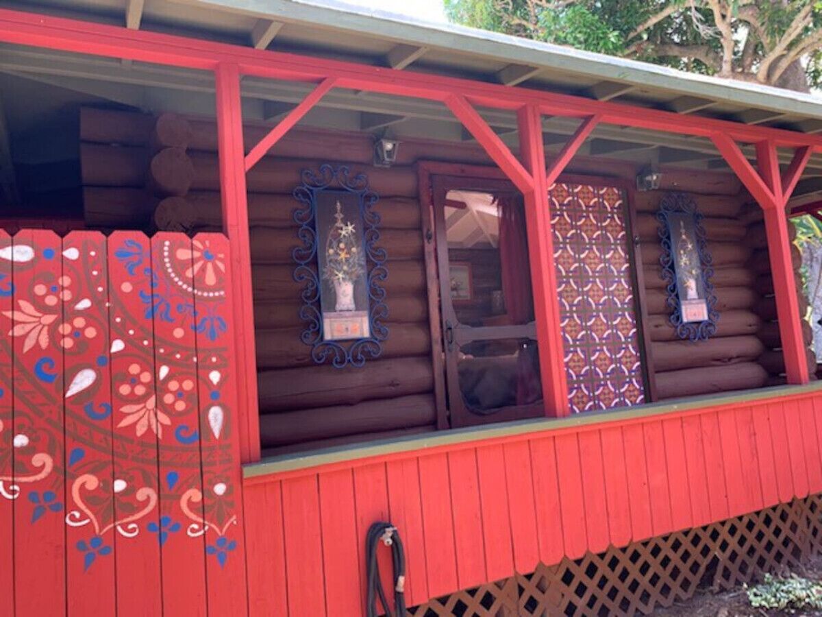 A log cabin with a red exterior and decorative window frames.