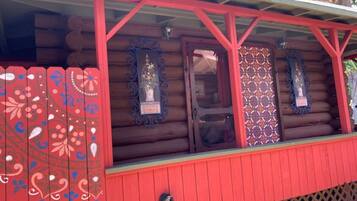 A log cabin with a red exterior and decorative window frames.