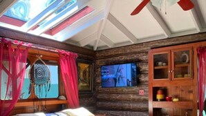 Une chambre confortable avec un lit, un ventilateur de plafond, une télévision et une armoire en bois.