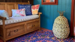 Une pièce chaleureuse avec un banc en bois, un ananas décoratif et un sol à motifs.