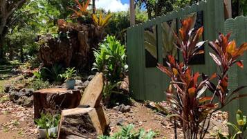 A garden with a wooden fence, a tree stump, and various plants.