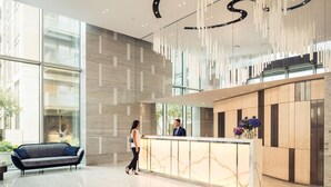 A spacious lobby with a reception desk, a sofa, and a large window providing natural light. - London Oasis Retreat With 2 Bedrooms - Fulham (London)