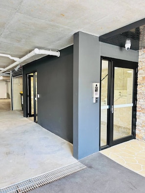 Un bâtiment moderne avec un plancher en béton, une porte noire et une caméra de surveillance.