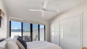 A bedroom with a bed, a ceiling fan, a sliding glass door, and a view of buildings outside. - Spacious Family 3BR Top-Floor Stay | Views, 2-Car Parking & EV-Friendly (Mount Gravatt East)