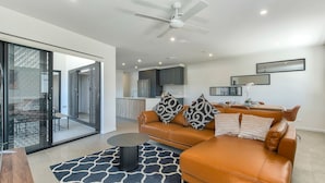 A modern living room with a leather sofa, a coffee table, and a patterned rug. - Spacious Family 3BR Top-Floor Stay | Views, 2-Car Parking & EV-Friendly (Mount Gravatt East)