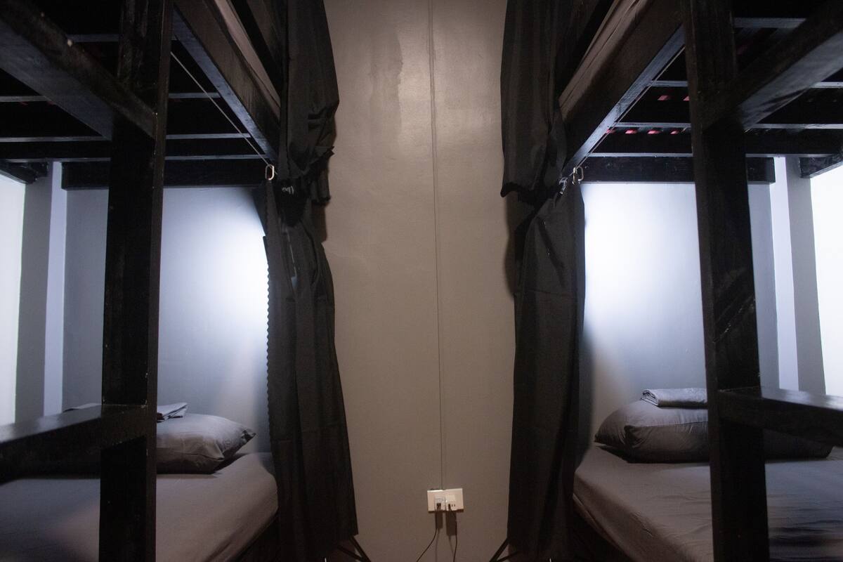 Ein Schlafraum mit Etagenbetten, einer schlichten Wand und einer Steckdose.