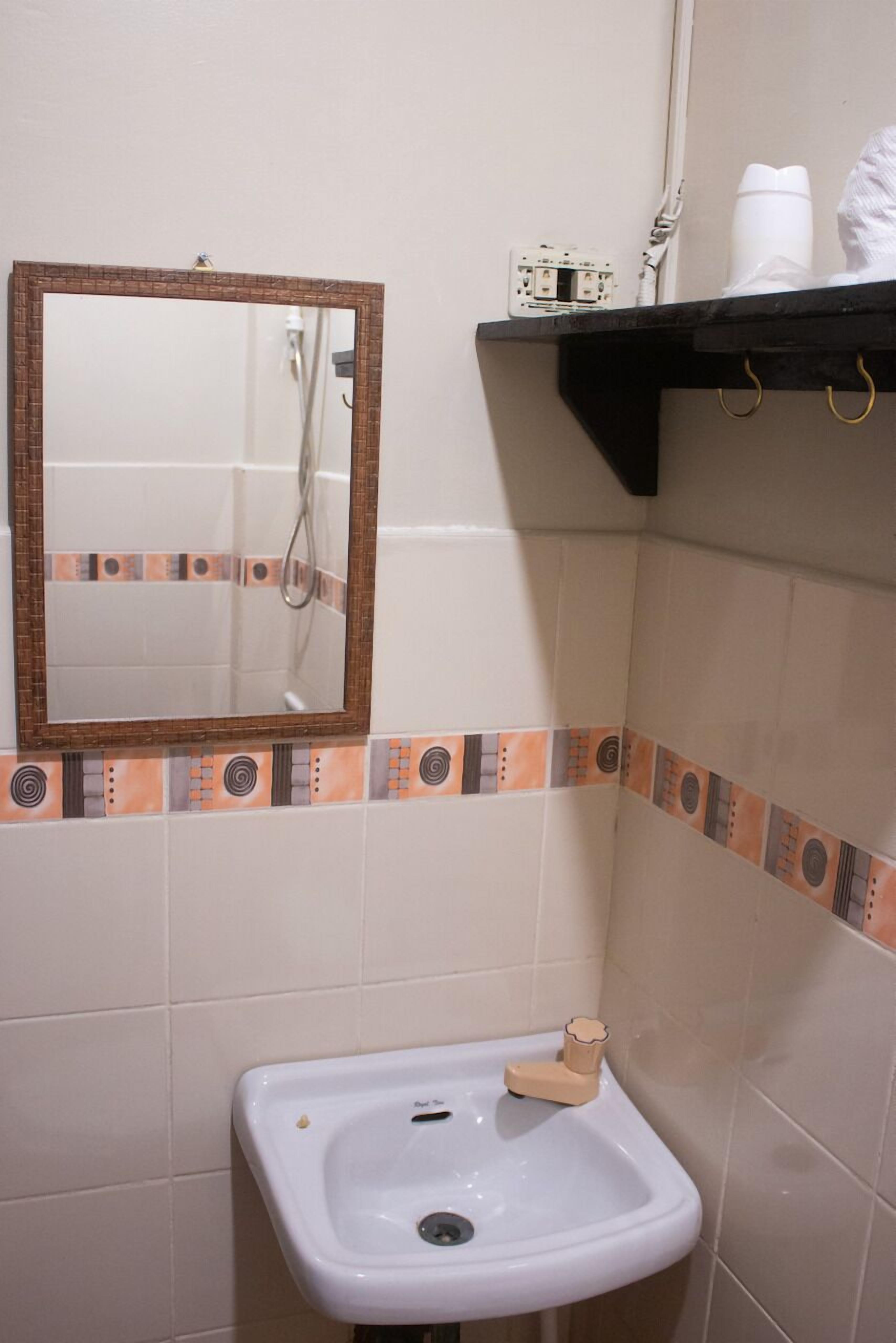 Un baño con un lavamanos blanco, un espejo y un estante con artículos de aseo.
