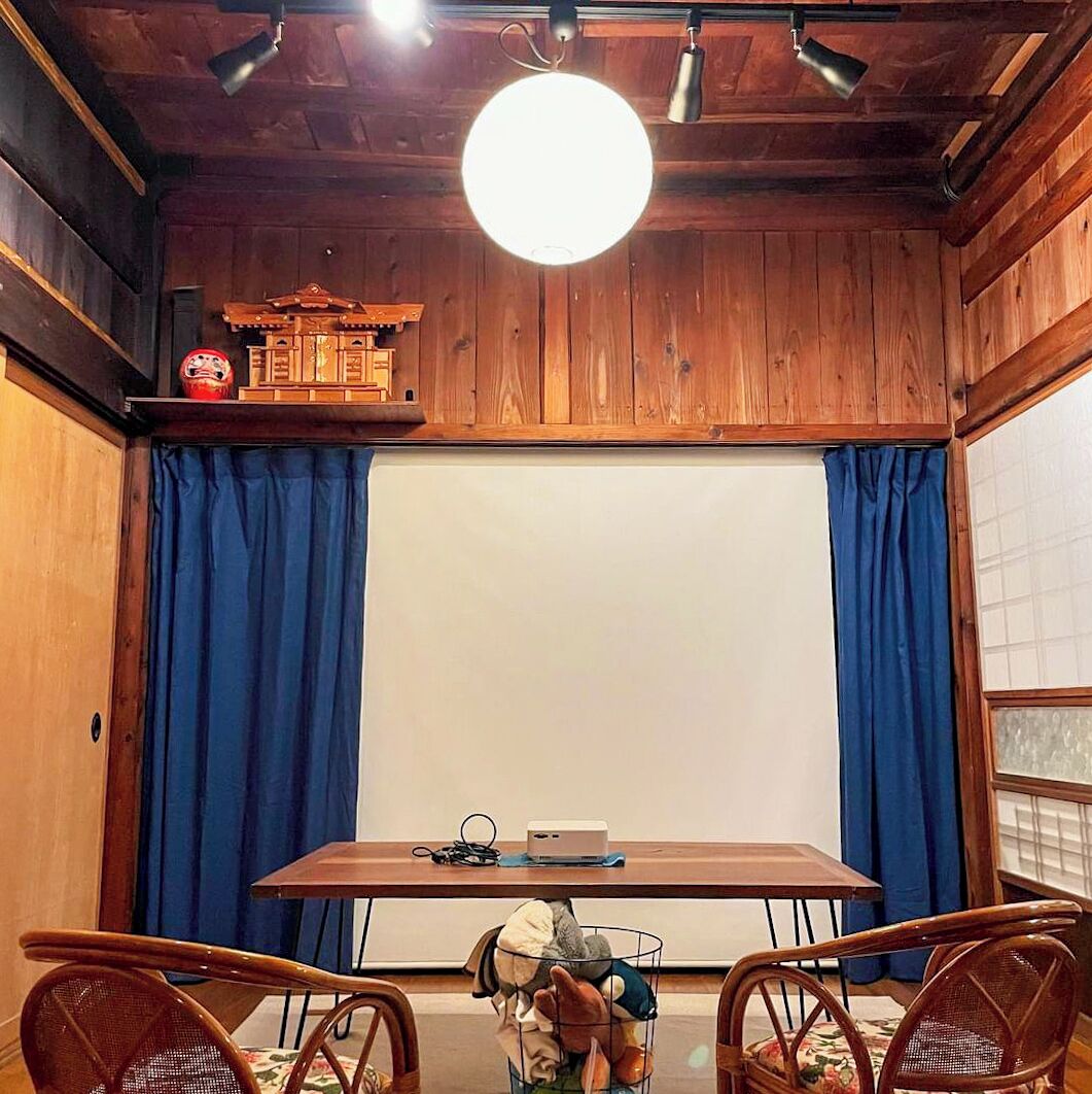 A room with a wooden ceiling, a round ceiling light, a whiteboard, and a table with chairs.