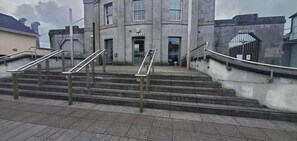 Un bâtiment abritant une bibliothèque et une entrée de musée, caractérisé par des marches en béton et des garde-corps en métal.