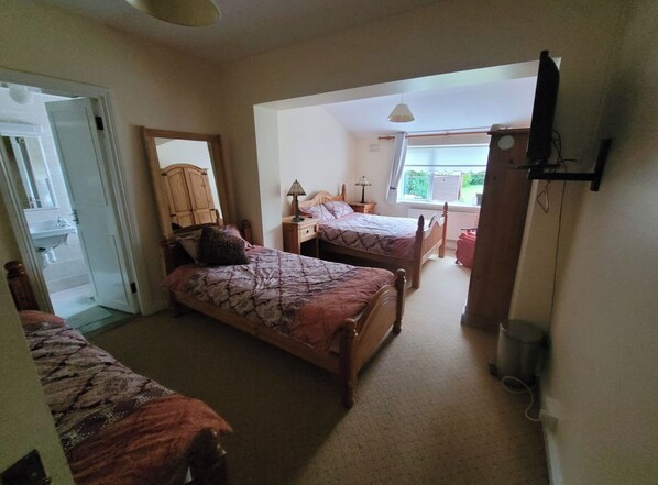 Une chambre avec deux lits, un bureau, une chaise, une lampe et une fenêtre.