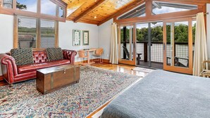 A spacious living room with a leather sofa, wooden coffee table, and a large rug. - Sleep Lakeside in Our Cozy Boathouse with Mtn Views (Landrum)
