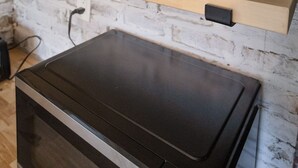 A kitchen with wooden shelves, a microwave, and a brick wall.