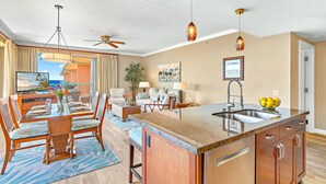 A spacious living area with a dining table, sofas, and a kitchen island.