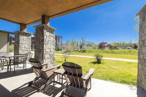 A covered patio area with stone pillars, outdoor seating, and a view of a residential neighborhood.