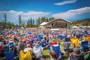 Un grand événement en plein air où les participants sont assis sur des rangées de chaises, face à une scène.