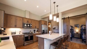 Una cocina moderna con armarios de madera, electrodomésticos de acero inoxidable y una isla central con taburetes de bar.
