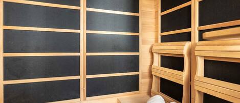 A sauna room with wooden benches and a bench with towels.