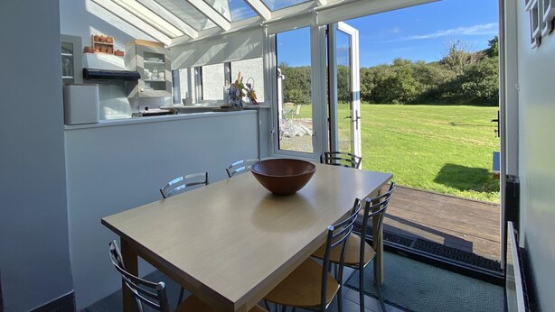 Une cuisine moderne dotée d’une grande fenêtre et d’un coin repas avec une table et des chaises en bois.