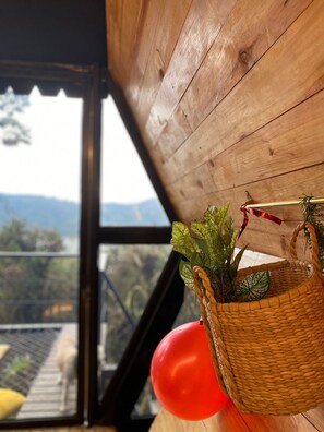 Uma cesta de vime com plantas sobre uma mesa de madeira, em um quarto com vista para montanhas através de uma janela.