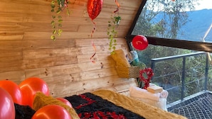 A room with wooden walls, a large window, and several red balloons. - Laguna Glamping (La Calera)