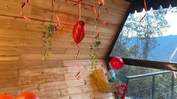 Una habitación con paredes de madera, un ventanal grande y varios globos rojos.