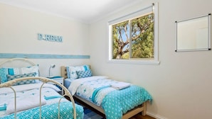 Un dormitorio con dos camas, una ventana con vista a un árbol y un letrero en la pared que dice 'DREAM'.