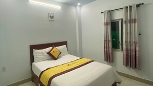 A neatly made bed with a white and yellow bedspread, a wooden headboard, and a single pillow with a logo. - Hai Yen Hotel Pleiku by Bay Luxury (Hoi Phu)