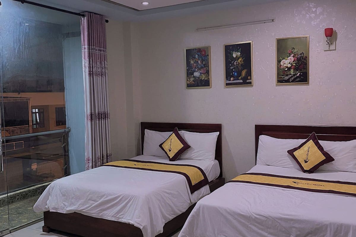 Habitación de hotel con dos camas, un separador de vidrio y obras de arte en las paredes.