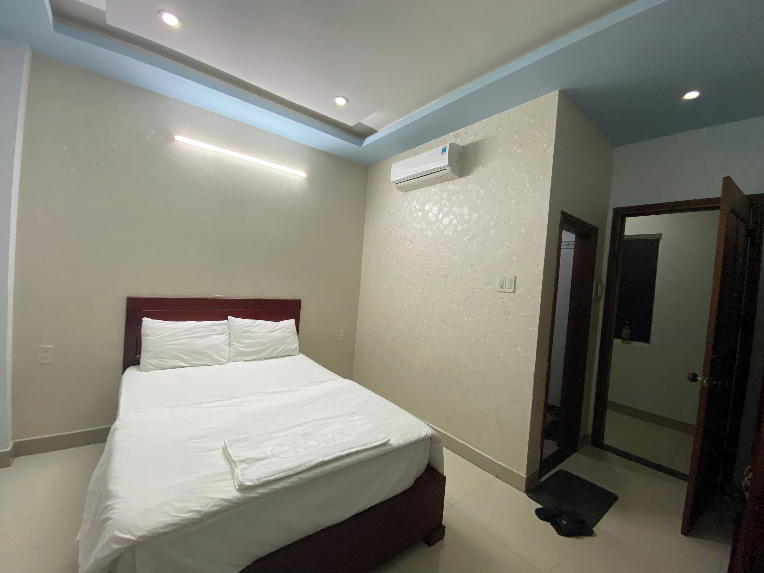 Habitación de hotel con una cama bien hecha, un equipo de aire acondicionado en la pared y una puerta que da a otra habitación.