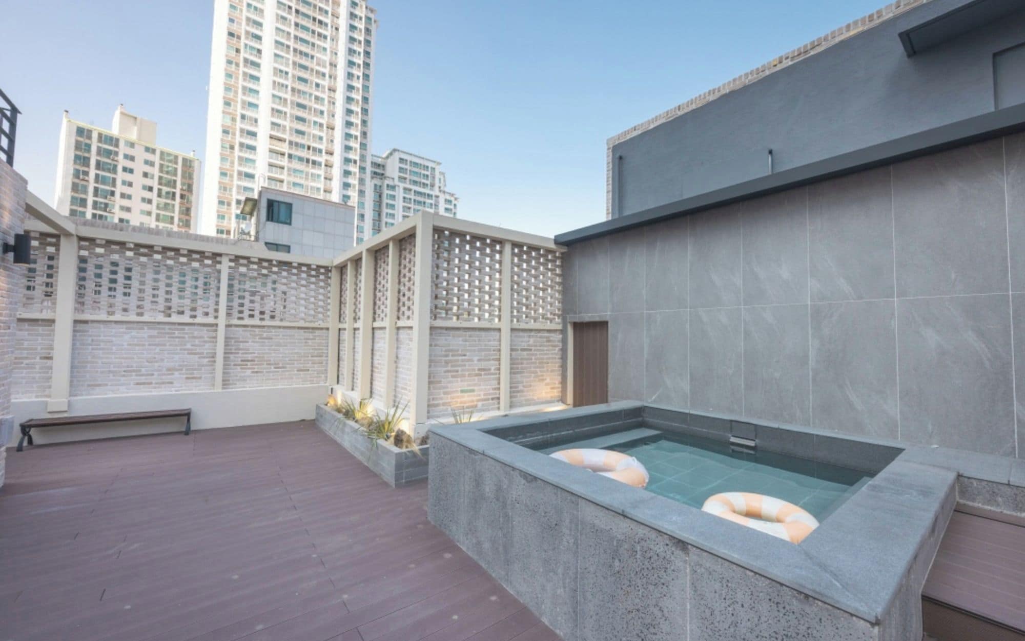 Un área de piscina en la azotea con vistas despejadas al horizonte de la ciudad, una terraza de madera y un diseño arquitectónico moderno.