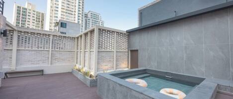 Un área de piscina en la azotea con vistas despejadas al horizonte de la ciudad, una terraza de madera y un diseño arquitectónico moderno.