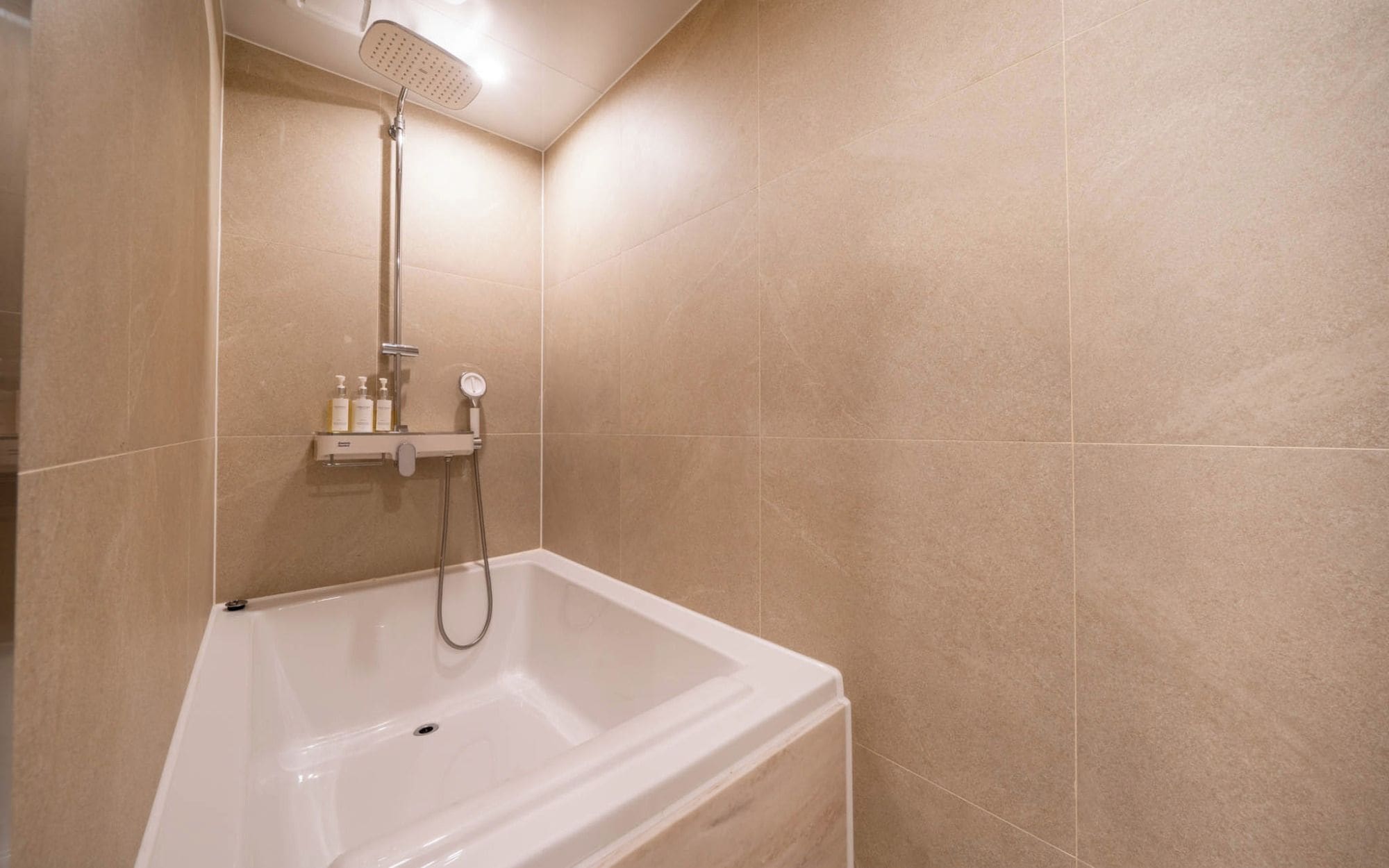 Ein Badezimmer mit einer Badewanne, einer Duschbrause und einem an der Wand befestigten Ablagefach mit Pflegeprodukten.